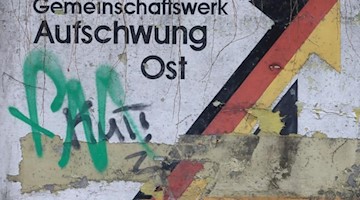 Der verwitterte Schriftzug «Gemeinschaftswerk Aufschwung Ost» in Magdeburg. Fot: Jens Wolf/Archivbild Foto: Jens Wolf