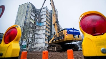 Ein etwa 100 Tonnen schwerer Spezialbagger reißt ein zehngeschossiges Wohnhaus ab. Foto: Jens Büttner/Archivbild