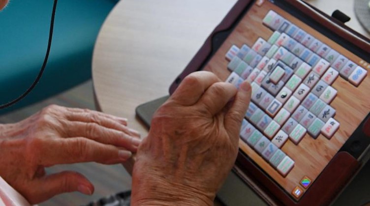 Eine Frau spielt im Seniorenheim mit ihrem Tablet Mahyong. Foto: Uwe Zucchi/Archivbild