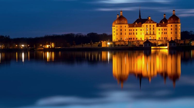 Das beleuchtete Schloss Moritzburg spiegelt sich am Abend in der blauen Stunde im Schlossteich. Foto: Monika Skolimowska/Archiv