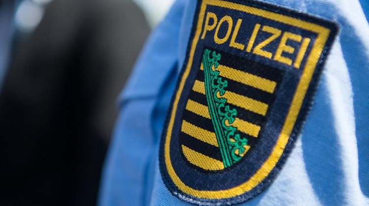 Das Logo der sächsischen Polizei ist an einer Polizeiuniform angebracht. Foto: Monika Skolimowska/Archivbild