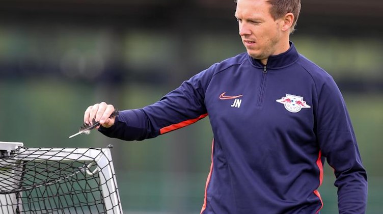 Der neue RB-Trainer Julian Nagelsmann sammelt eine Vogelfeder während einer Trainingseinheit vom Platz auf. Foto: Jan Woitas/Archivbild