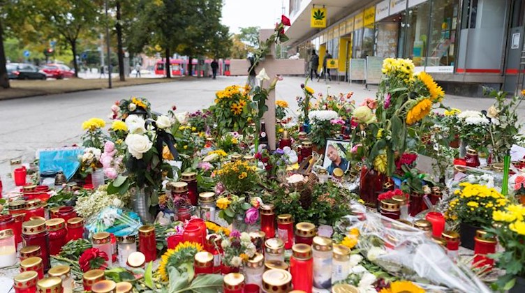 Ein Holzkreuz und ein Foto des Opfers stehen zwischen zahlreichen Blumen und Kerzen am Tatort. Foto: Monika Skolimowska/Archivbild