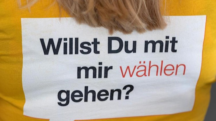 Auf einem T-Shirt einer jungen Frau steht «Wilst Du mit mir wählen gehen?». Foto: Robert Michael/Archivbild