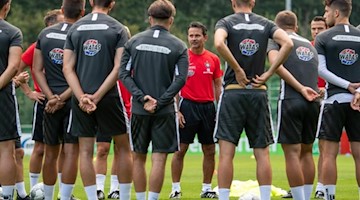 Dirk Schuster (M), neuer Trainer vom FC Erzgebirge Aue, hält eine Ansprache an die Spieler. Foto: Robert Michael/Archivbild