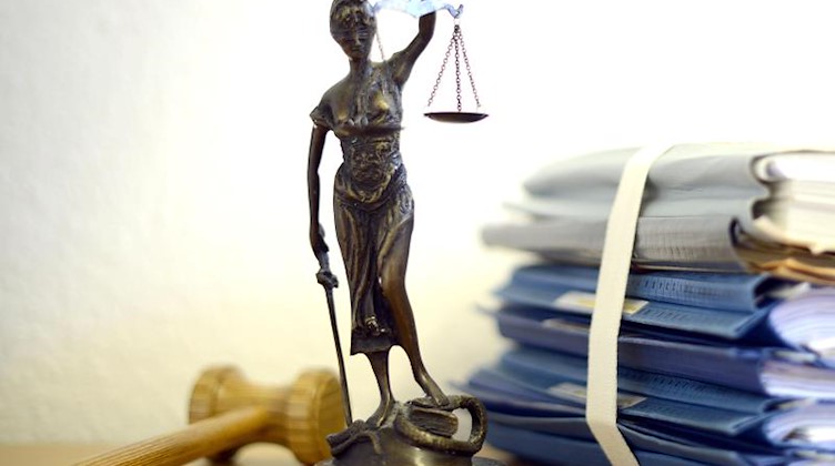 Die modellhafte Nachbildung der Justitia steht neben einem Holzhammer und einem Aktenstapel auf einem Tisch. Foto: Volker Hartmann/Archivbild