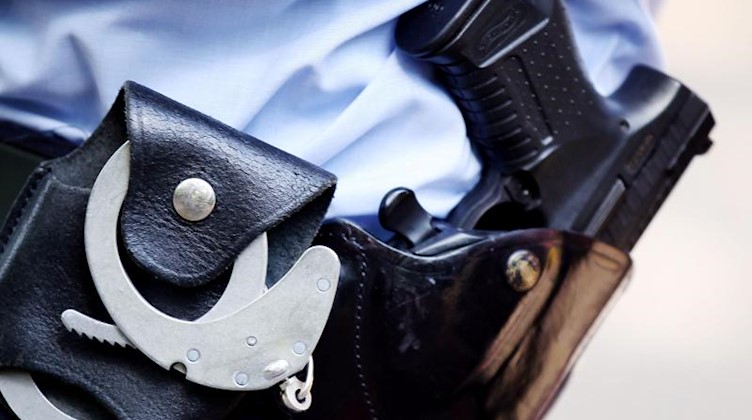 Ein Polizist mit Handschellen und Pistole am Gürtel. Foto: Oliver Berg/Archivbild