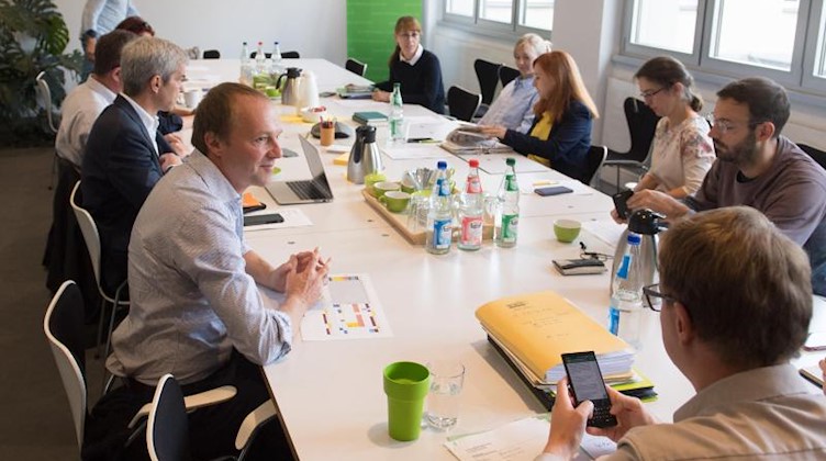 Wolfram Günther (l) und weitere Teilnehmer der Konstituierung der Grünen sitzen im Fraktionssaal. Foto: Sebastian Kahnert