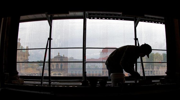 Ein Arbeiter zeichnet sich an einem demontierten Fenster ab. Foto: Arno Burgi/Archivbild