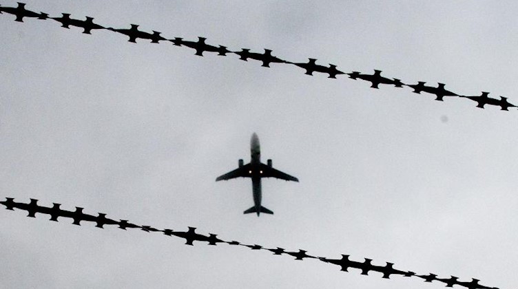 Ein Flugzeug ist hinter Stacheldraht zu sehen. Foto: Julian Stratenschulte/Archivbild
