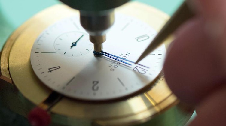 Ein Uhrmacher justiert in der Uhrenmanufaktur Nomos die Zeiger des Uhrenmodells Tangente 33. Foto: Sebastian Kahnert/Archivbild