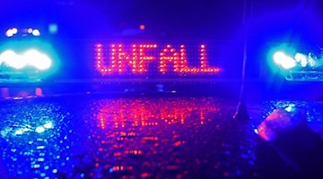Während einer Unfallaufnahme spiegelt sich das Blaulicht und der Schriftzug "Unfall" auf dem Dach eines Polizeiwagens. Foto: Stefan Puchner/Archiv