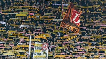 Fans von Dynamo Dresden halten Schals hoch. Foto: Robert Michael/Archivbild