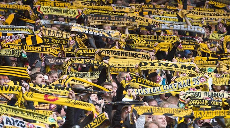 Die Fans von Dynamo Dresden halten ihre Fanschals in die Höhe. Foto: Sebastian Kahnert/Archivbild