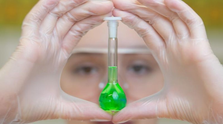 Eine Schülerin hält ein Reagenzglas mit grüner Flüssigkeit in der Hand. Foto: Sebastian Kahnert/Archivbild
