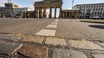 An der Stelle, wo zu DDR-Zeiten die Berliner Mauer stand, sind Pflastersteine, die an Mauerzeiten errinern. Foto: Christophe Gateau/Archivbild