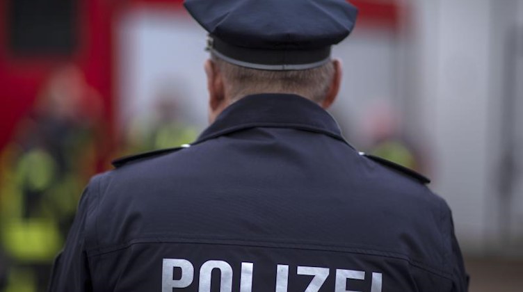 Polizisten der Landespolizei stehen vor einem Polizeifahrzeug. Foto: Jens Büttner/Archivbild