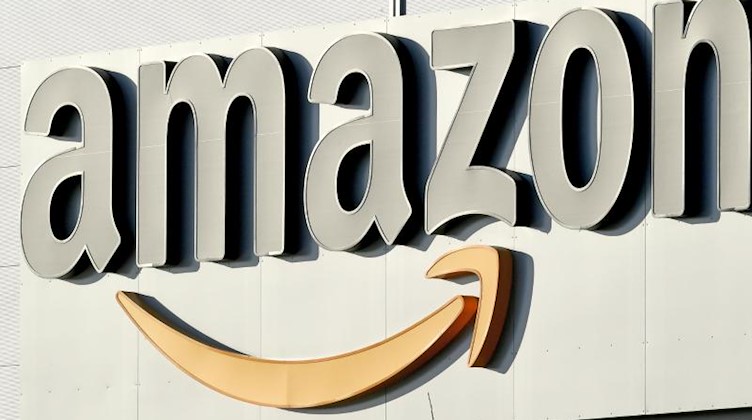 Logo und Schriftzug von Amazon an einem Paketzentrum des Online-Händlers. Foto: Holger Hollemann/Archivbild