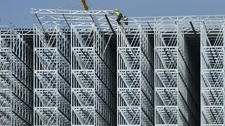Bauarbeiter errichten die Stahlkonstruktion für ein Logistikzentrum mit Büros und einem Warenlager. Foto: Martin Schutt/Archivbild