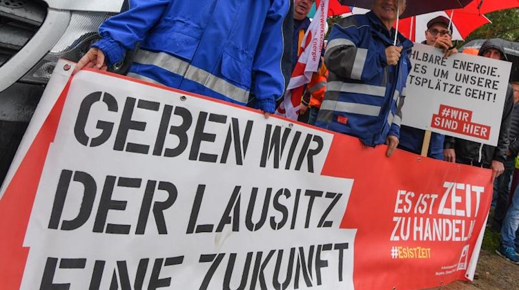 Ein Banner mit der Aufschrift «Geben wir der Lausitz eine Zukunft» wird von Demonstranten in die Luft gehalten. Foto: Patrick Pleul/zb/dpa