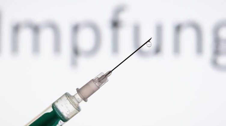 Eine Spritze wird vor den Schriftzug "Impfung" gehalten. Foto: Friso Gentsch/dpa