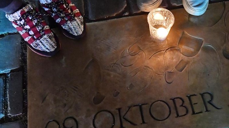Besucher des Lichtfestes haben auf einer Gedenkplatte mit der Aufschrift "09. Oktober 1989" eine Kerze abgestellt. Foto: Hendrik Schmidt/dpa-Zentralbild/dpa