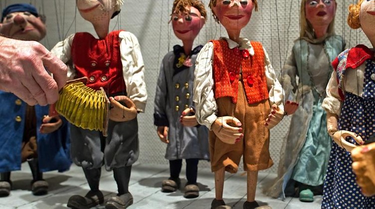 Ein Mann richtet eine Puppe aus der Sammlung des Puppentheaters Zwickau. Foto: Arno Burgi/dpa-Zentralbild/dpa