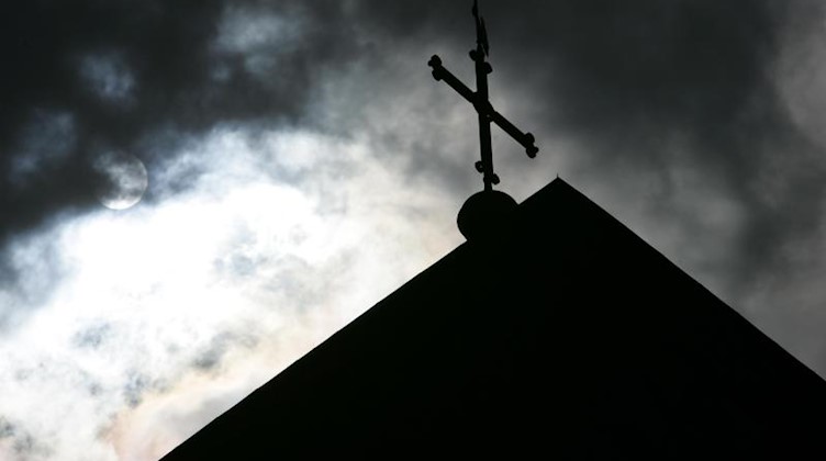 Kreuz im Gegenlicht. Foto: Friso Gentsch/dpa
