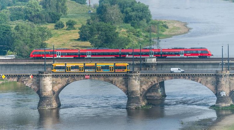 Eine Regionalbahn und eine Straßenbahn überqueren in Dresden auf der Marienbrücke die Elbe. Foto: Robert Michael/zb/dpa/Archivbild