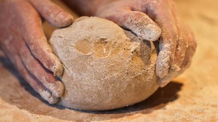 Ein Bäcker formt mit seinen Händen ein Brot. Foto: Jan Woitas/zb/dpa