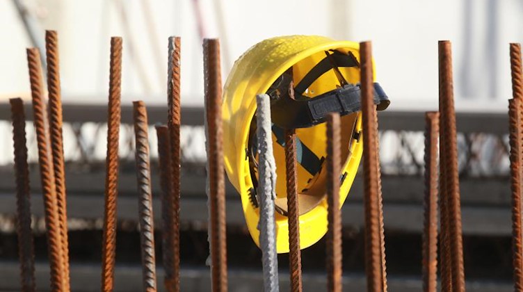 Ein Bauhelm hängt an Fundament-Stangen auf einer Baustelle. Foto: Bodo Schackow/dpa/Archivbild