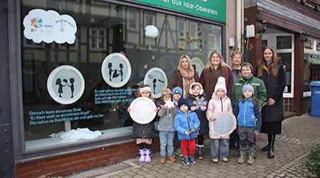 Die Erzieherinnen Simone Böhler, Svenja Moll, Kathrin Berg (Leitung) und Jana Haberland mit einigen ihrer Schützlinge vor dem von ihnen dekorierten Schaufenster in der Burgstraße. Ganz rechts ist Hann. Mündens Wirtschaftsförderin Anna-Lena Wiegräfe zu sehen, Ideengeberin des Projekts "Advent in Kinderhand". Foto: Stadt HMÜ