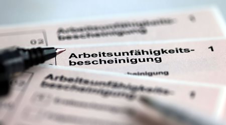 Stifte liegen auf Arbeitsunfähigkeitsbescheinigungen für Arbeitnehmende im Falle einer Krankschreibung durch den Arzt. / Foto: Jens Büttner/dpa/Symbolbild