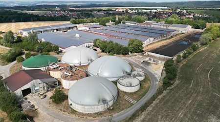 Blick auf eine Biogasanlage einer Agragenossenschaft. Dahinter sind Gebäude mit Solarpanelen zu sehen. / Foto: Bodo Schackow/dpa/Archivbild