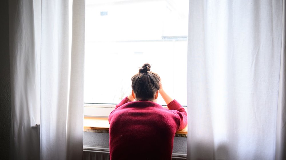 Eine Frau sitzt mit Kopf in den Händen am Fenster. / Foto: Jonas Walzberg/dpa/Symbolbild