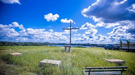 Ein großes eisernes Kirchenkreuz steht vor einer imposanten Wolkenkulisse auf dem Bremer Berg über dem Camper See. / Foto: Jens Büttner/dpa-Zentralbild/dpa