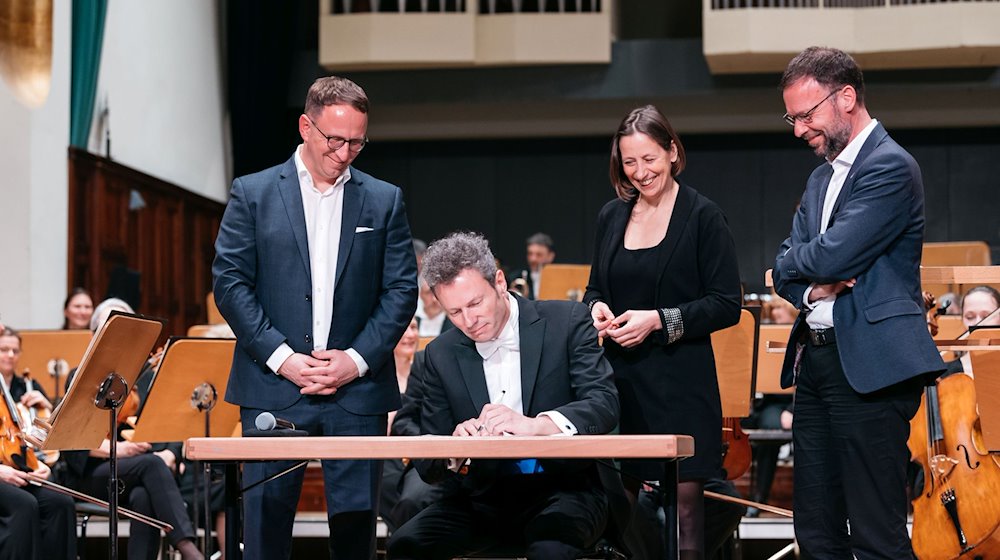 Simon Gaudenz (2.v.l) unterzeichnet seine Vertragsverlängerung als Generalmusikdirektor bei der Jenaer Philharmonie. / Foto: Christoph Worsch/Jenaer Philharmonie//JenaKultur/dpa