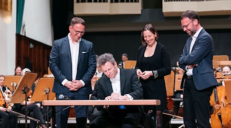 Simon Gaudenz (2.v.l) unterzeichnet seine Vertragsverlängerung als Generalmusikdirektor bei der Jenaer Philharmonie. / Foto: Christoph Worsch/Jenaer Philharmonie//JenaKultur/dpa