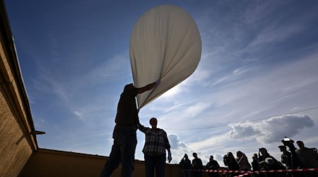 Forscher starten einen Stratosphärenballon auf dem Dach des Hauptgebäudes der Physikalisch-Astronomischen Fakultät der Friedrich-Schiller-Universität Jena. / Foto: Martin Schutt/dpa