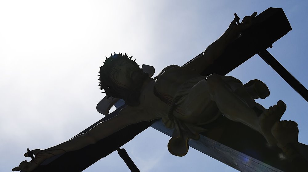Gläubige tragen bei der Palmsonntagsprozession im Eichsfeld eine überlebensgroße Darstellung "Kreuzigung", die das Leiden und Sterben Jesu Christi symbolisiert. / Foto: Swen Pförtner/dpa-Zentralbild/dpa