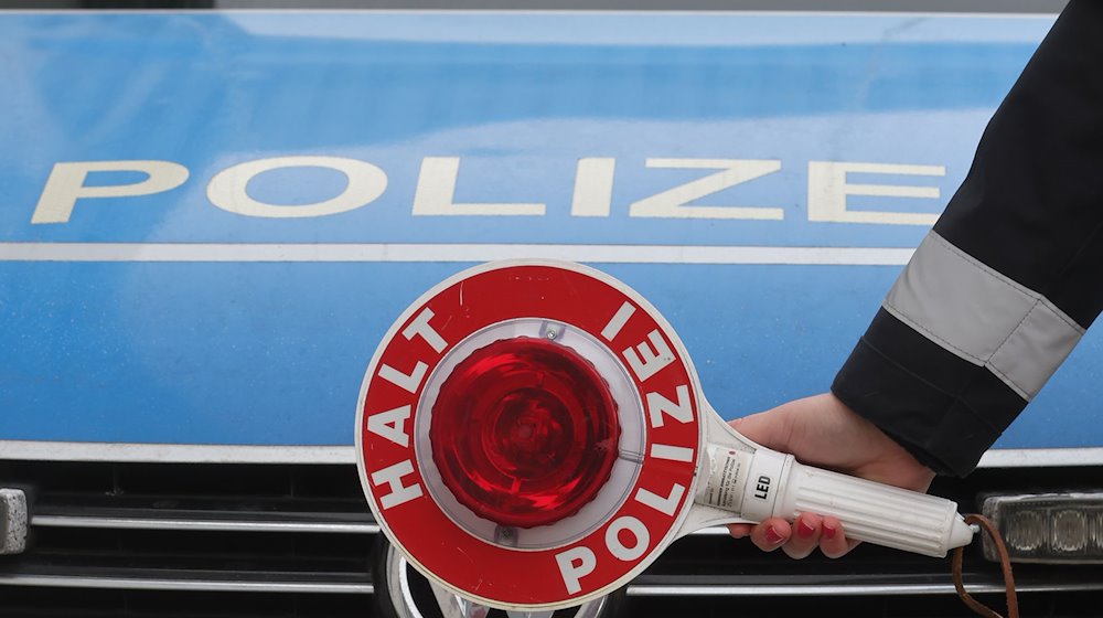 Eine Anhaltekelle vor einem Dienstauto der Thüringer Polizei. / Foto: Bodo Schackow/dpa