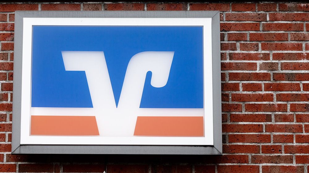 Das Logo der Volks- und Raiffeisenbanken hängt über einer Geschäftsstelle. / Foto: Markus Scholz/dpa