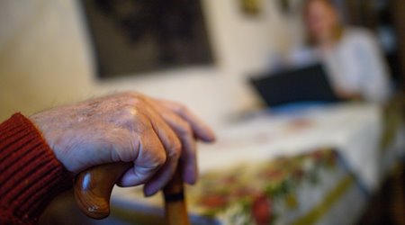 Eine Pflegebegutachterin sitzt während eines Gesprächs mit einem älteren Mann, der mit einem Gehstock an einem Tisch sitzt. / Foto: Klaus-Dietmar Gabbert/dpa