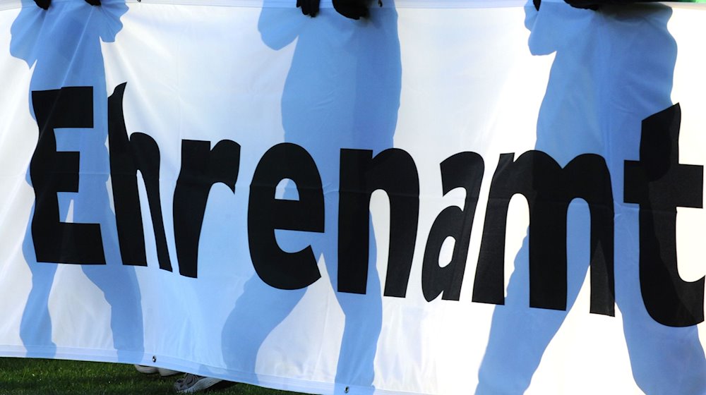 Jugendliche halten vor einem Fußball-Bundesligaspiel ein Banner mit der Aufschrift «Ehrenamt» in den Händen. / Foto: Patrick Seeger/dpa/Archivbild