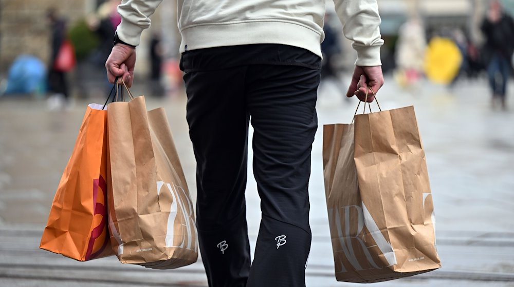 Ein Mann trägt Einkaufstüten durch die Innenstadt. / Foto: Martin Schutt/dpa-Zentralbild/dpa