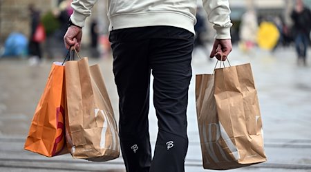 Ein Mann trägt Einkaufstüten durch die Innenstadt. / Foto: Martin Schutt/dpa-Zentralbild/dpa