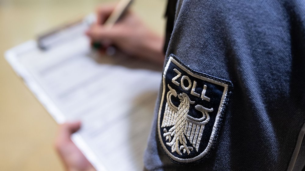 Ein Zollbeamter füllt ein Dokument aus. / Foto: Hendrik Schmidt/dpa/Illustration