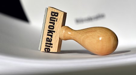 Ein Stempel mit der Aufschrift «Bürokratie» liegt auf Papieren. / Foto: Ralf Hirschberger/dpa-Zentralbild/dpa/Symbolbild