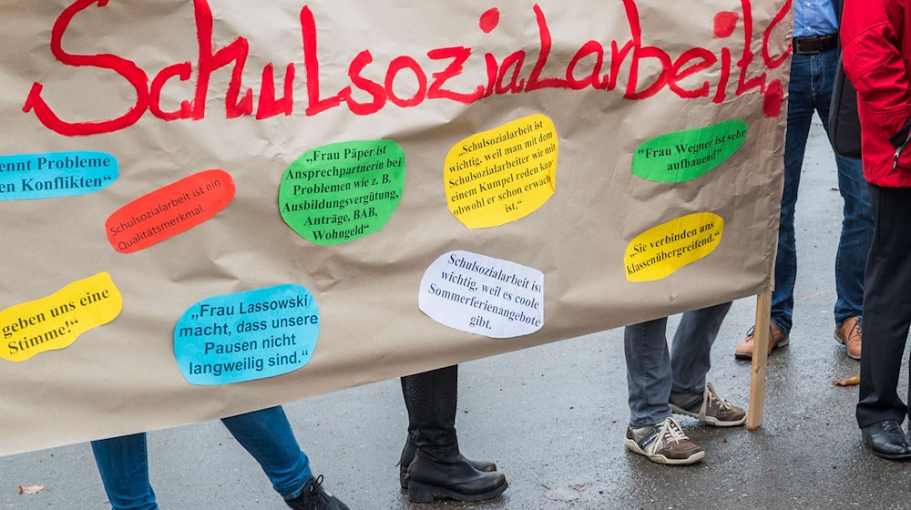 Teilnehmer einer Demonstration halten ein Plakat mit der Aufschrift «Schulsozialarbeit» hoch. / Foto: Jens Büttner/dpa-Zentralbild/dpa