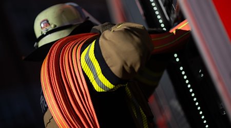 Ein Feuerwehrmann nimmt einen Schlauch aus einem Einsatzfahrzeug. / Foto: Marijan Murat/dpa/Archivbild